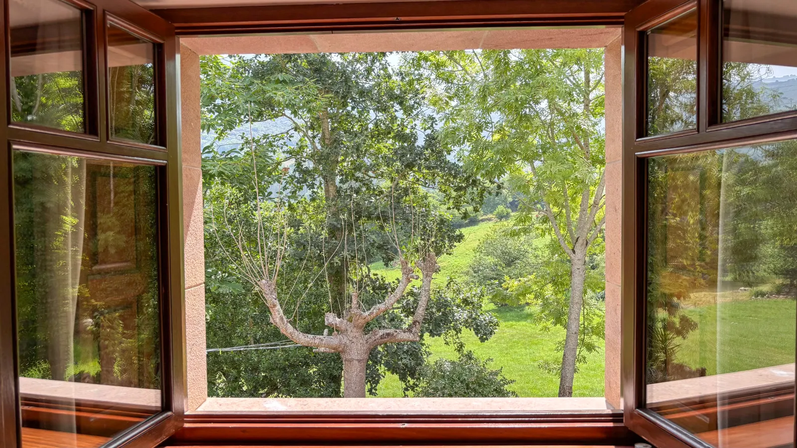 Ventana de madera abierta al verde de Cantabria