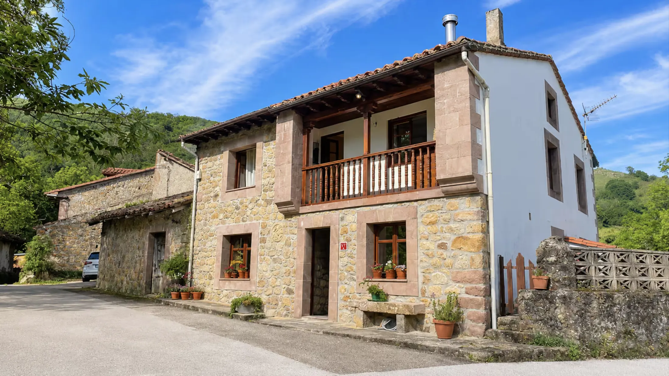 Fachada de piedra de Casa El Robreo con los montes de Cantabria al fondo