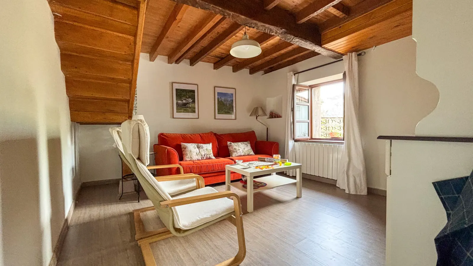 Salón de Casa El Robreo con sofá, vigas de madera y chimenea